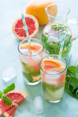 Refreshment grapefruit cocktail with mint on mint color background. Healthy citrus summer drink.