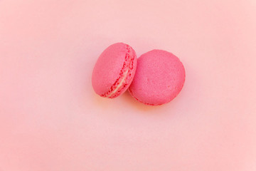 Top view of mini pink macaron or macaroon french desserts cake on soft sweet pink pastel paper flat lay background