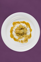 Simple dish from India. Chicken Korma. Chicken on a mildly spiced coconut creamy sauce served with rice on white plate.