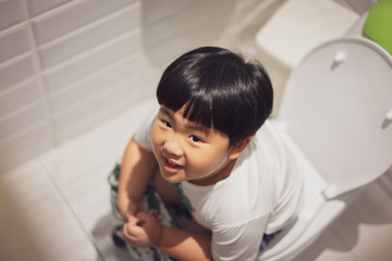 A boy is sitting on toilet with suffering from constipation