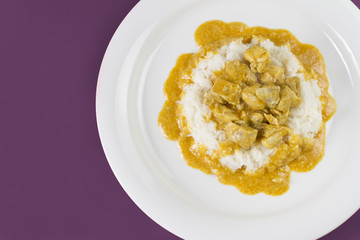 Simple dish from India. Chicken Korma. Chicken on a mildly spiced coconut creamy sauce served with rice on white plate.