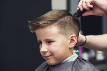 European boy  getting hairstyle in barbershop. - 203121023