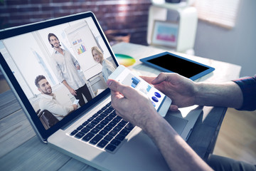 Business interface against cropped hand of graphic designer using smartphone and laptop