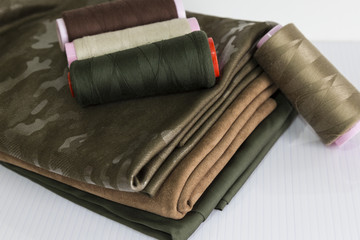 sewing materials are blue,brown,grey and cream color bobbin with the colorful fabric for textile concept.