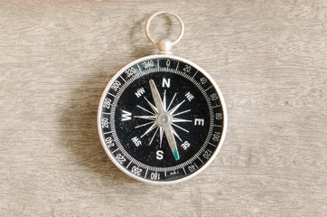 Old compass on wooden table.