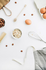 Flat lay, top view of raw healthy food ingredients. Cutting board, hazelnuts, eggs, cereals. Cooking concept.