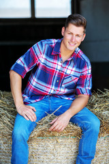 blond man in jeans sitting on haystack