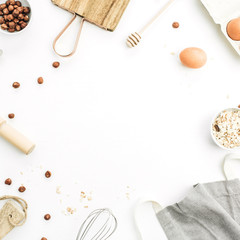Frame of food ingredients on white background. Cooking flat lay, top view concept. Eggs, apron, cutting board, hazelnut, cereals on white background. Mock up.