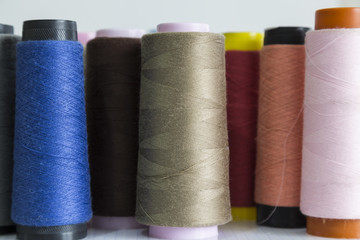 sewing materials are blue,brown,grey and cream color bobbin for textile concept.