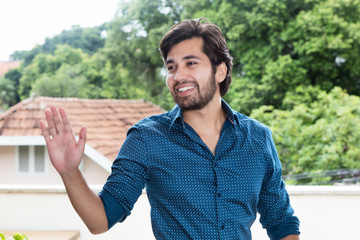 Hispanic hipster man with beard greeting a friend