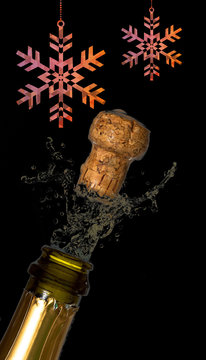 Hanging snowflake against close up of champagne cork popping