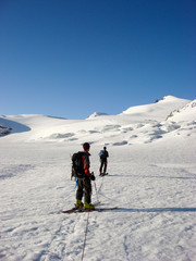 Fototapeta na wymiar two male backcountry ski mountaineers head towards a high alpine peak over a long glacier between Saas Fee and Zermatt
