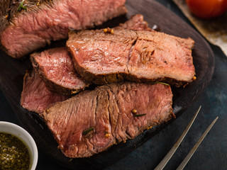 Sliced Roast beef on cutting board with grilled vegetables .