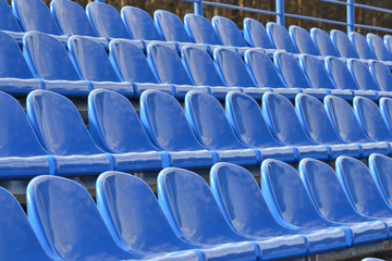 Rows of blue seats in the stands. Athletic facilities.