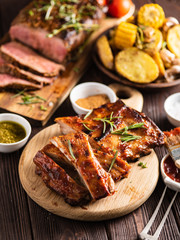 Delicious barbecued ribs seasoned with a spicy basting sauce and served with chopped fresh vegetables on an old rustic wooden chopping board