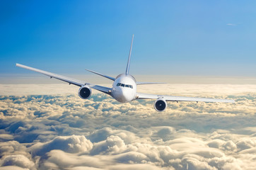 Naklejka premium Samolot pasażerski lecący na poziomie lotu wysoko na niebie nad chmurami i wschodem słońca błękitnego nieba.