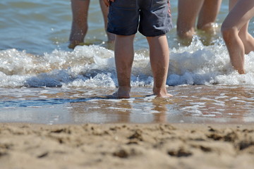 Children play on the beach, and piss their feet in the water