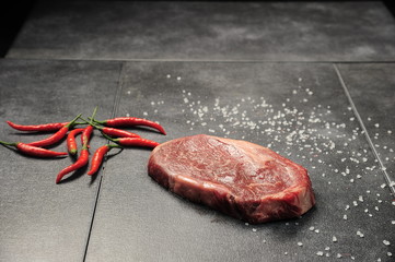 Raw meat on a dark gray surface and ingredients for cooking. Food background.