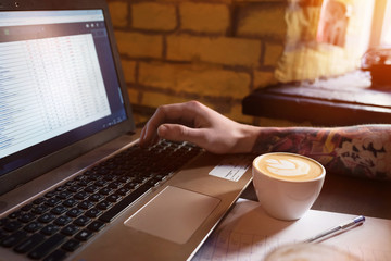 Fresh coffee for wonderful ideas. A man working on a notebook in a cafe.