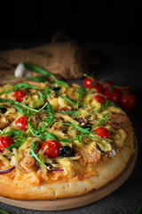 Pizza with chicken, arugula, cheese and onions on wooden rustic table