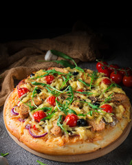 Pizza with chicken, arugula, cheese and onions on wooden rustic table