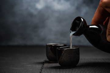 Man pouring sake into sipping bowl