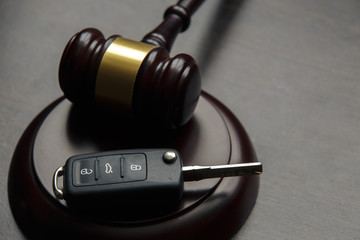 Close-up Of Gavel And Car Key On Sounding Block Against Grey Background