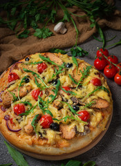 Pizza with chicken, arugula, cheese and onions on wooden rustic table. Top view