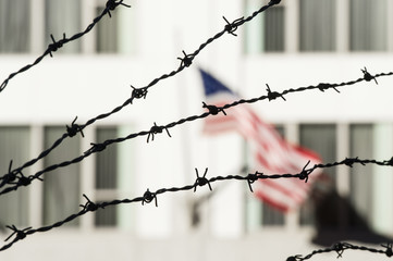 Fototapeta na wymiar Barbed wire in the foreground and the blurred American flag in the background. Manhattan, New York city, USA.