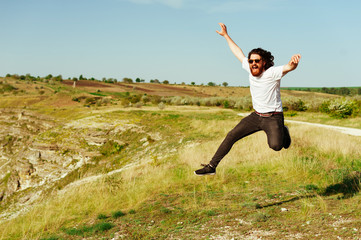 celebrating success outdoors concept - fun modern man jumping with arms raised with energy for...