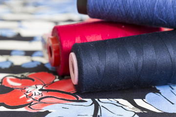 red,blue and navy blue bobbin on the colorful fabric for textile concept.