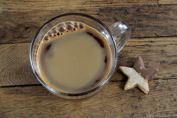 Cup of coffee and star-shaped chocolate cookie on wooden background. Top view.
