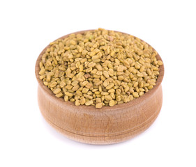 Fenugreek seeds in wooden bowl, isolated on white background