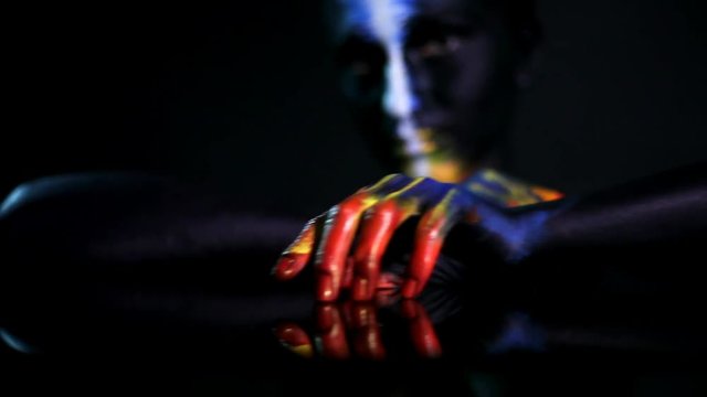 Hands of a dark-skinned glowing girl with color make-up