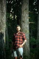 Naklejka na ściany i meble Brutal lumberjack in woods. Bearded guy holding small spade in his hands. Environment and nature concept
