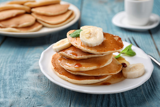 Tasty pancakes with honey and banana on table