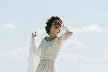 retro style and makeup for young woman in white dress. retro woman pose on blue sky background in vintage style