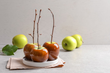 Plate with delicious green caramel apples on table