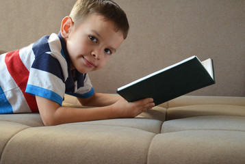Little boy reading book on a floor at home
