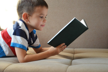 Little boy reading book on a floor at home