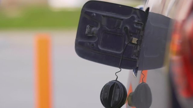 A woman runs a gasoline car at a gas station. Close-up.