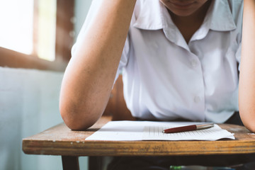 Close up the pen and students writing and reading exam answer sheets exercises in classroom of school with stress.