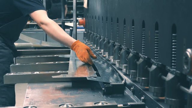 Factory worker operates with a CNC guillotine shears 