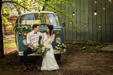 Cheerful happy young couple sit on the bumper retro-minibus.