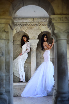 Fashion model or princess in dress. Wedding fashion and beauty salon. Bride girls at wedding ceremony in castle. Sexy girls in white dress with stylish hair. Women at stone ancient column in summer.