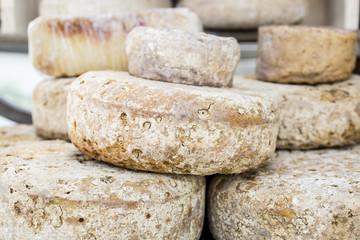 rustic french cheese wheels stacked on the marketplace