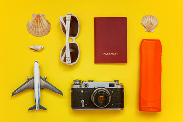 Flat Lay with plane, vintage camera, passport, globe, sunglasses and shell on yellow colourful trendy modern fashion background. Vacation travel summer weekend sea adventure trip concept