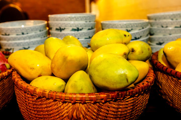 Yellow mango lie in the basket on the counter in the lacquer of Chinese food