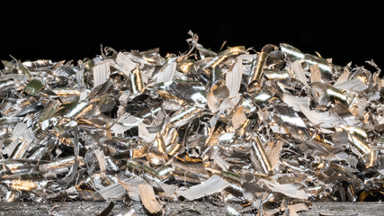 Tangle of glossy metal shavings. Close-up of the pile of manufacturing metallic chips on black...