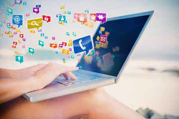 Woman sitting on beach using her laptop with colourful computer applications